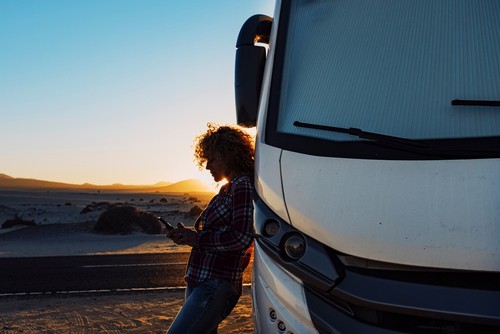 Person leaning up against an RV with a sunset