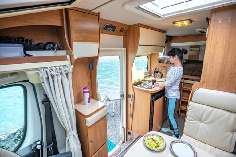 Person in an RV kitchen preparing a meal