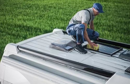 man on top of an rv cleaning and using rv sealant