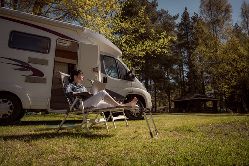 person sitting outside their RV with a laptop fully charged to the internet