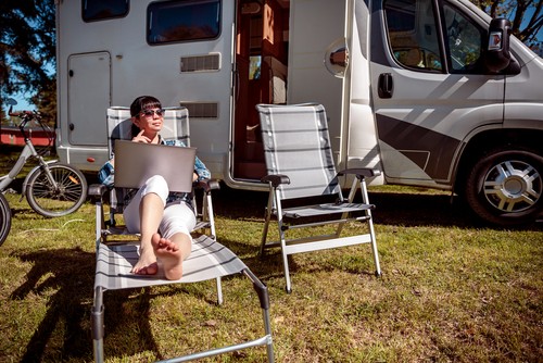 person outside their RV with internet connection on their laptop